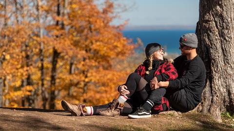 A couple sitting under a tree at the top of Blue Mountain