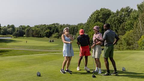 A group of people talking on a golf course.