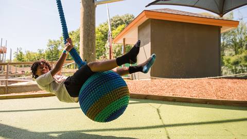 a boy swinging in the cocoon crawl playscape