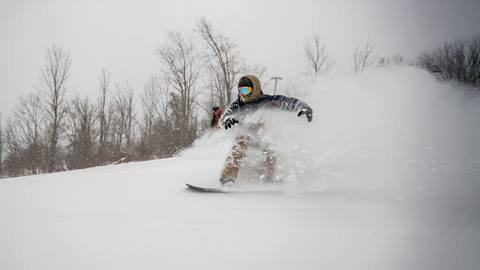 a man riding a snowboard down a snow covered slope