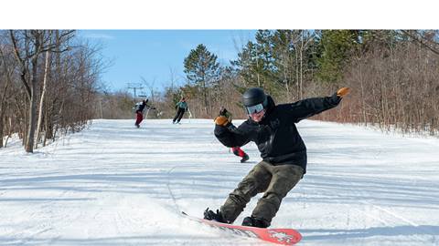 A man riding a snowboard down a snowy slope.