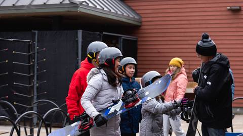 A group of people holding skis in front of a building.