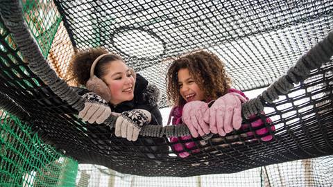 two girls enjoying the Canopy Climb Net Adventure in the Winter time