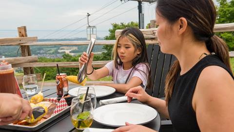 a woman and a girl sitting at a table with plates and drinks at the Summitview Mountaintop at Blue Mountain Resort