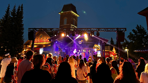 An outdoor night-time concert with a live band performing on stage to an audience.