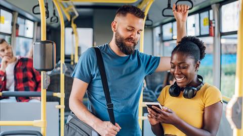 Two people on a bus looking at their phones.