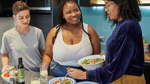 Three women are preparing food in a kitchen.