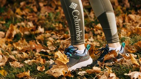 A person stands on autumn leaves wearing columbia leggings and hiking shoes.