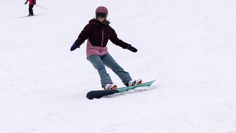 A woman snowboarding down Smart Alec Trail