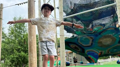 a young boy standing in front of the cocoon crawl climbing net at blue mountain resort