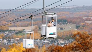 People riding up Gondola at Blue Mountain in Fall to see trees changing Colour