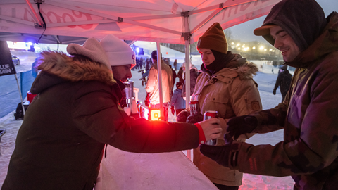 A group of people standing at a bar in the snow.