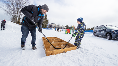 A man and boy playing hockey in the snow.