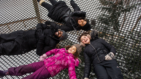 A group of people laying on a trampoline in the snow.