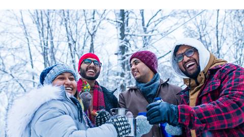 A group of friends enjoying a drink in a snowy forest.