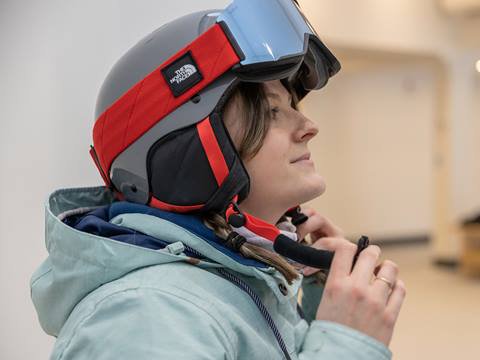 A woman wearing a ski helmet in a room.