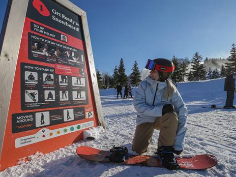 A snowboarder reading one of the Snow How Pillars