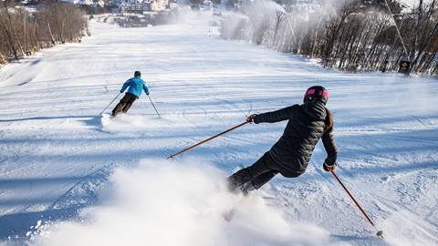 A man and a woman skiing down Blue Mountain